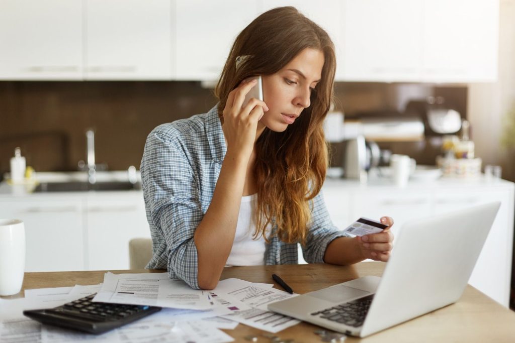 A woman checks her credit card and bills while considering debt consolidation to better manage expenses.